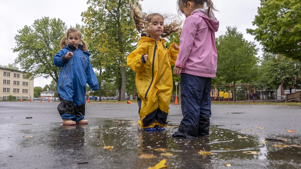 Trois enfants jouent dans une flaque d'eau.