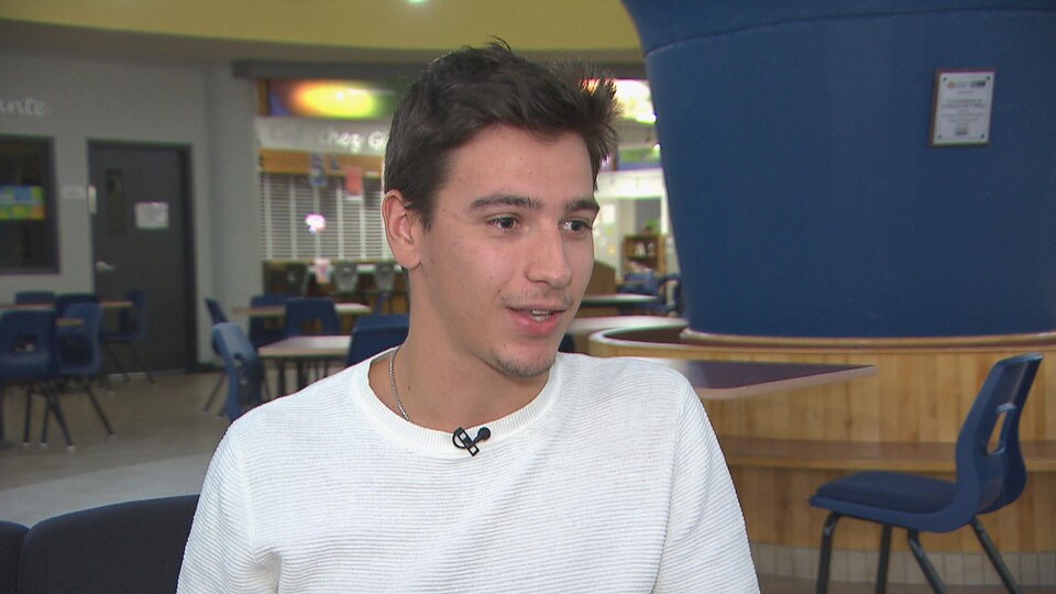 Mathias Leduc accorde une entrevue à Radio-Canada. Il est au Cégep de Jonquière dans un atrium.