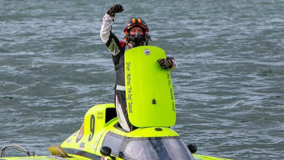 Un homme fait un signe de victoire dans une embarcation