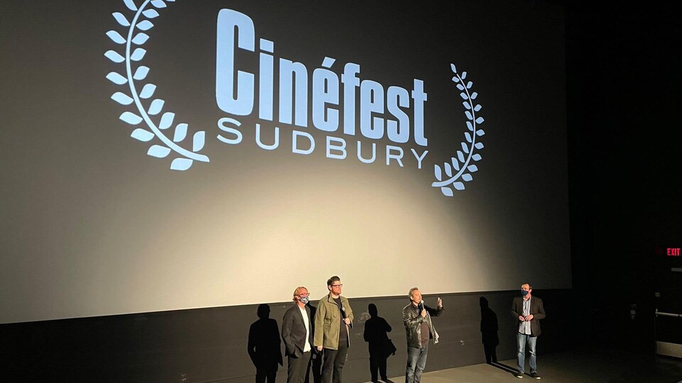 Mathieu Séguin se tient debout sur la scène de projection du Cinefest de Sudbury en compagnie de trois autres collaborateurs.