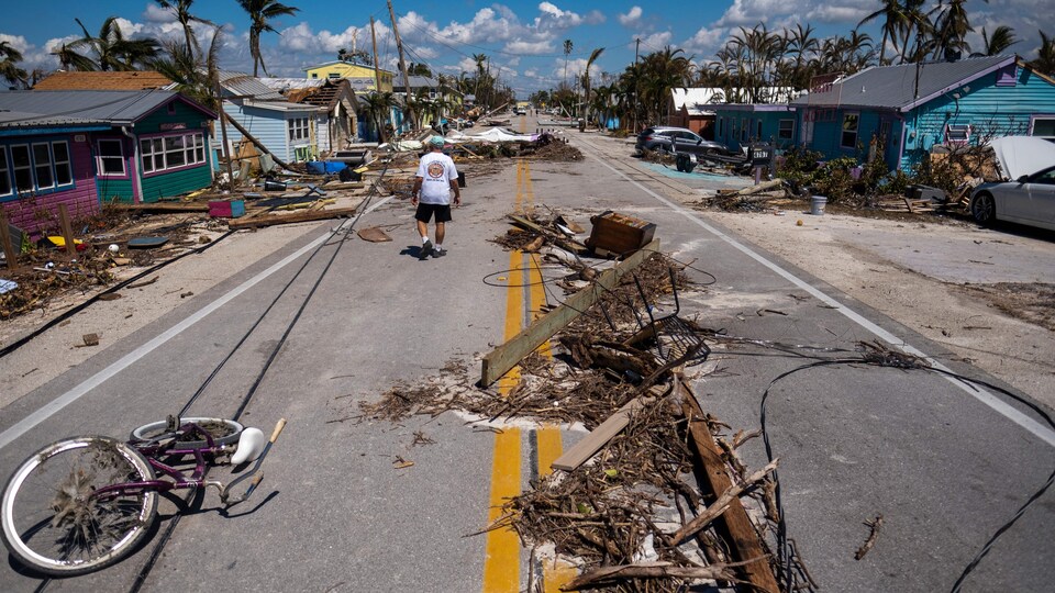 Un homme marche près de débris éparpillés sur Pine Island Road après le passage de l'ouragan Ian à Matlacha, en Floride, le 1er octobre 2022.