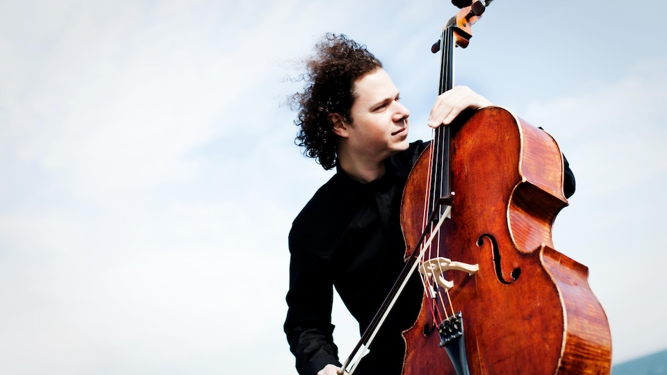 Le violoncelliste Matt Haimovitz est photographié avec son instrument de musique. Il regarde au loin. 