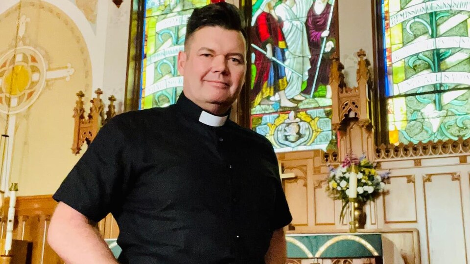 Un prête pose en quilt devant l'autel dans une église.