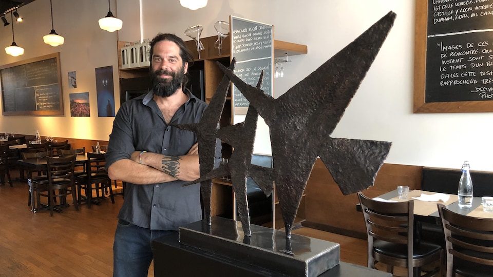 Matthieu Binette pose à côté de ses sculptures à l'intérieur du restaurant Auguste.