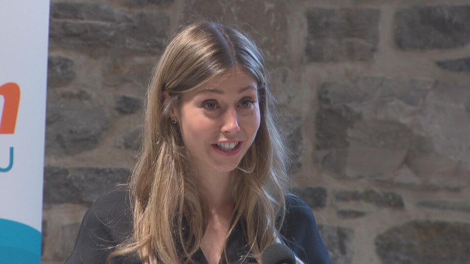 Une femme prononce un discours en souriant.