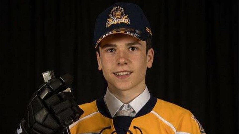 Un jeune homme avec un uniforme de hockey sourit.