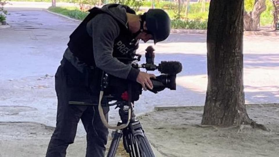 The cameraman-editor leaned over his camera, which was mounted on a tripod.