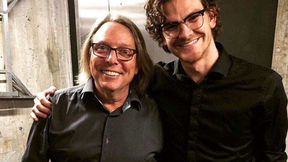 Un jeune homme pose avec Robert Paquette.