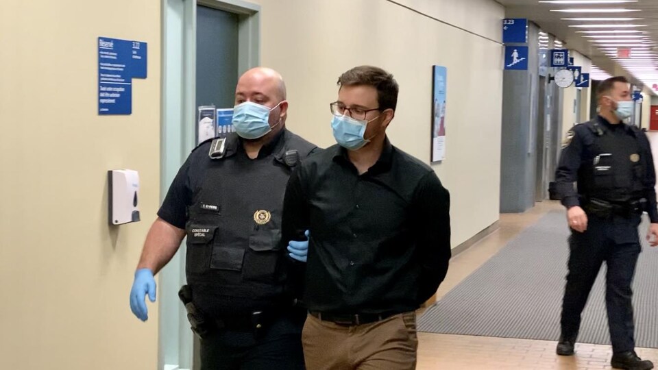 Maxime Lehoux, menotté, est escorté vers les cellules du palais de justice de Québec.