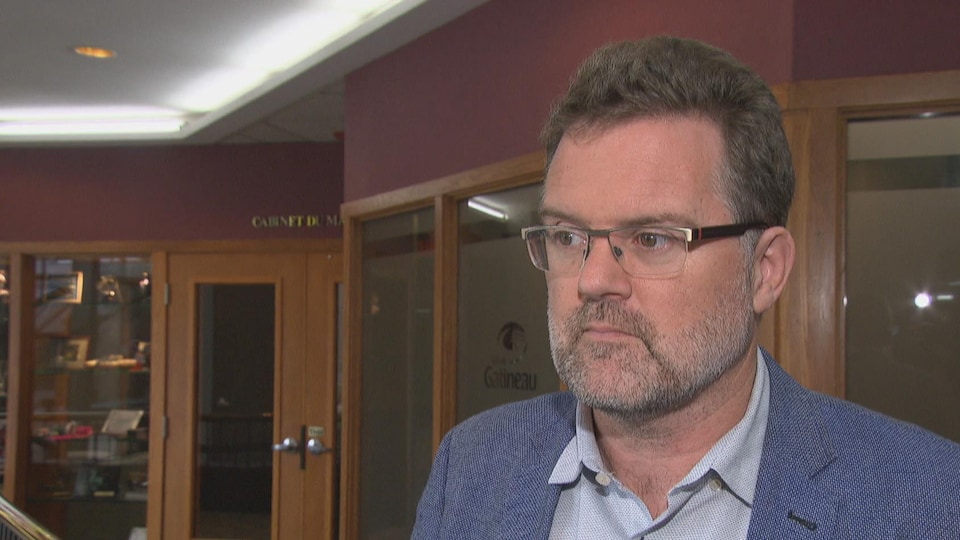Un homme dans l'hôtel de ville de Gatineau en entrevue avec un média.