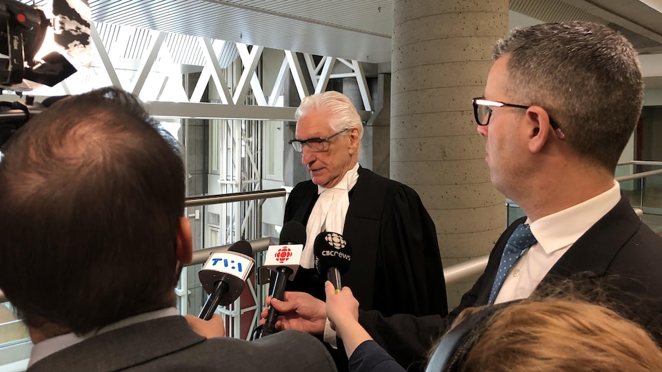 Me Guy Bertrand répond aux questions des journalistes dans les couloirs du palais de justice de Québec.