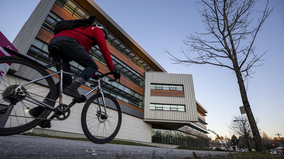 Un cycliste roule devant le siège social de Mountain Equipment Coop à Vancouver.