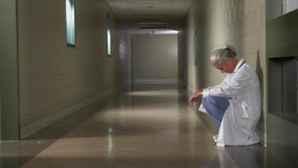 Une femme médecin est accroupie dans le corridor d'un hôpital.