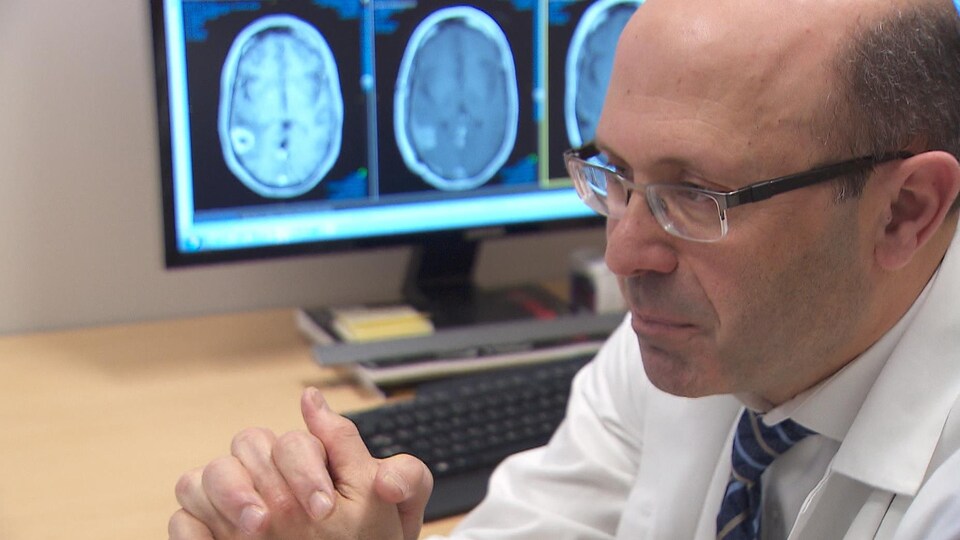 Le docteur Bassam Abdulkarim est assis à son bureau devant des images d'un scan du cerveau.