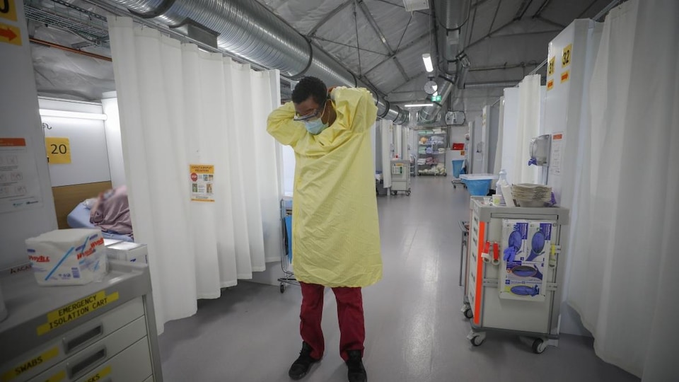 Un employé de l'hôpital met son masque.