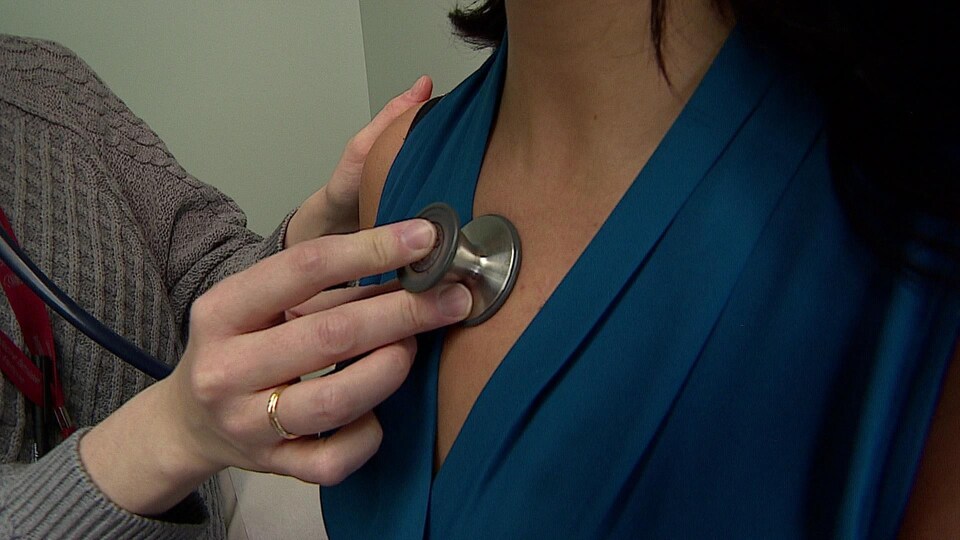 Photo d'un médecin qui ausculte une femme.