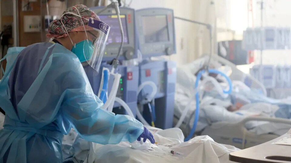 Une infirmière s'occupe d'un patient dans une salle de soins intensifs.
