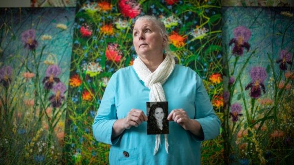 Portrait d'une mère tenant dans ses mains une photo de sa fille.