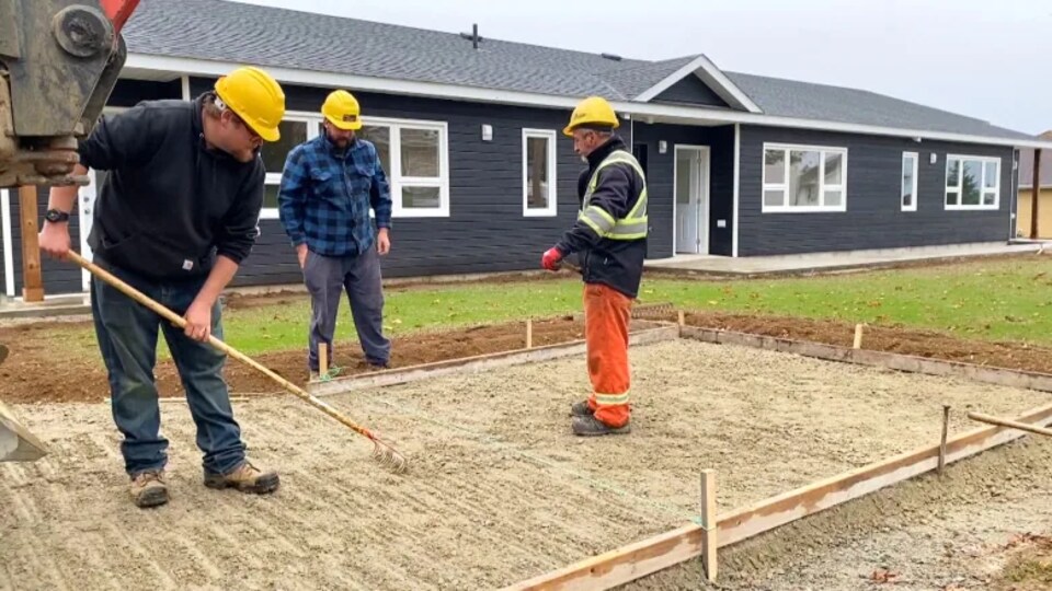 Trois travailleurs de la construction préparent une entrée de ciment.