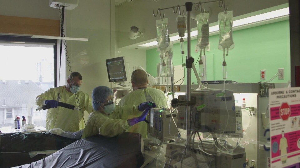 Du personnel soignant s'occupe d'un malade de la COVID-19 allongé dans son lit à l'Hôpital Saint-Paul de Vancouver.