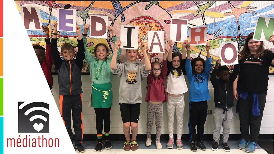 Des enfants tiennent des lettres pour former le mot « Médiathon »