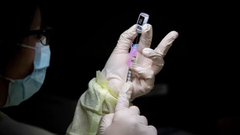 Une infirmière prépare un vaccin.