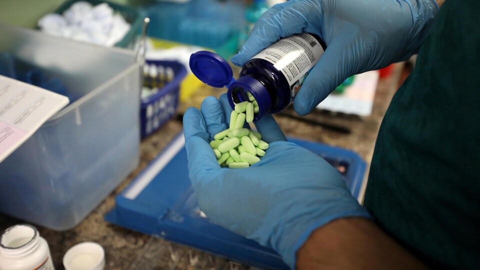 Gros plan sur les mains d'un pharmacien comptant les comprimés d'un flacon.