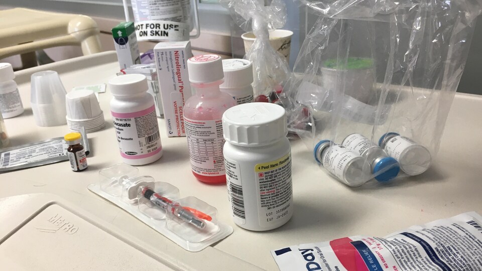 Des bouteilles de médicaments et des seringues sur une table d'hôpital. 