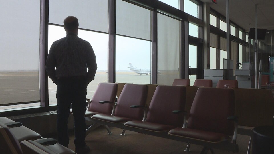 Le responsable de l'aéroport de Medicine Hat, Jeff Huntus, regarde un jet privé sur la piste depuis la salle d'attente vide.