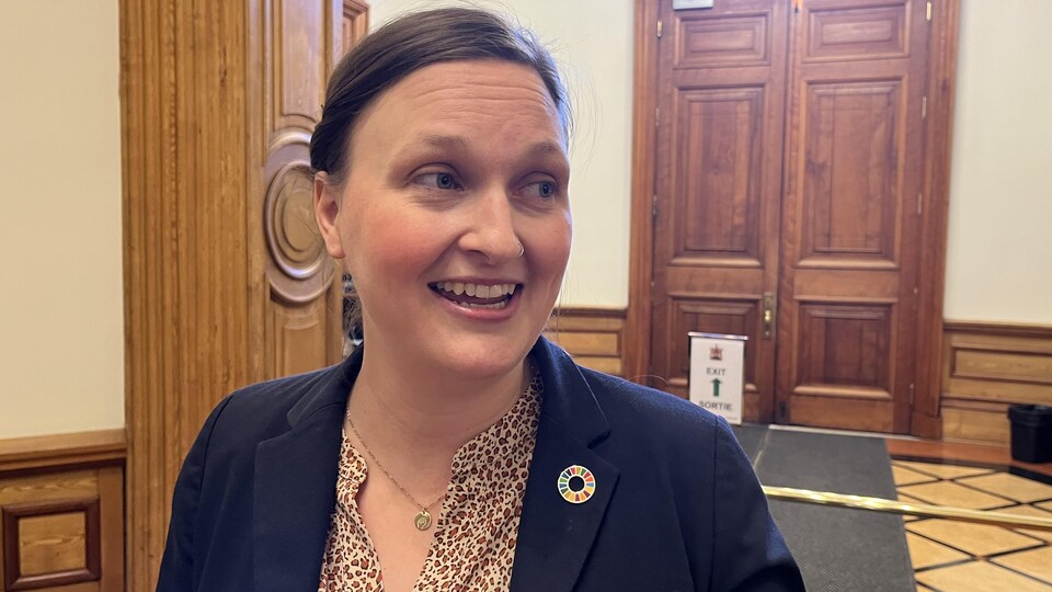 Megan Mitton regarde à sa gauche en souriant dans les couloirs du bâtiment de l'Assemblée législative.