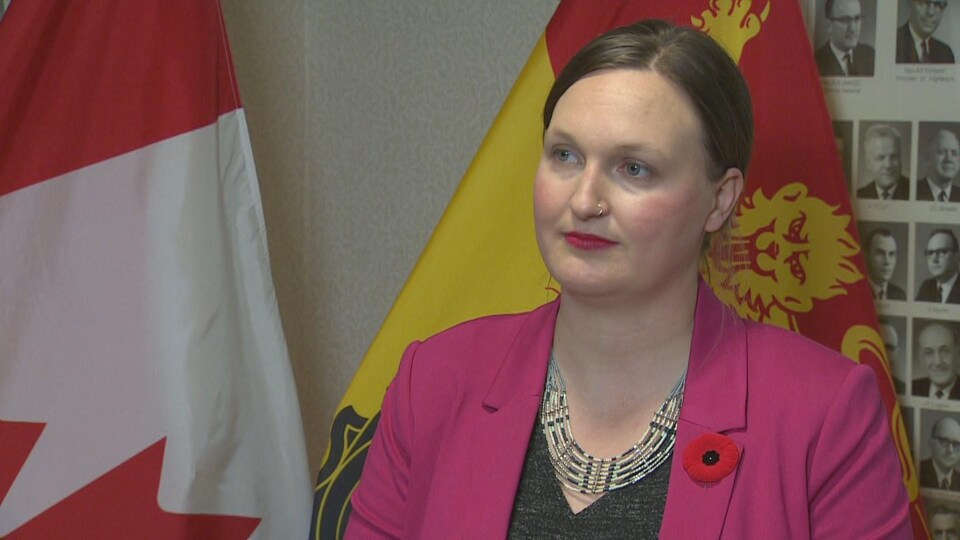 Megan Mitton lors d'une entrevue devant des drapeaux du Canada et du Nouveau-Brunswick.
