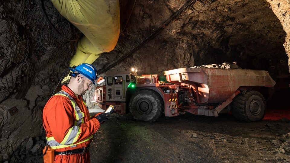 Un mineur travaille sur une tablette sous terre.