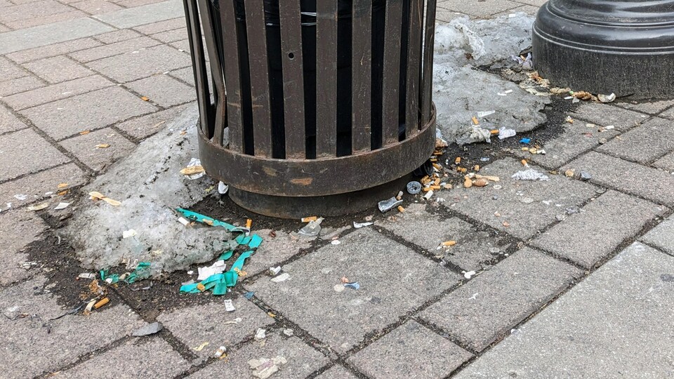 Des mégots de cigarettes près d'une poubelle.
