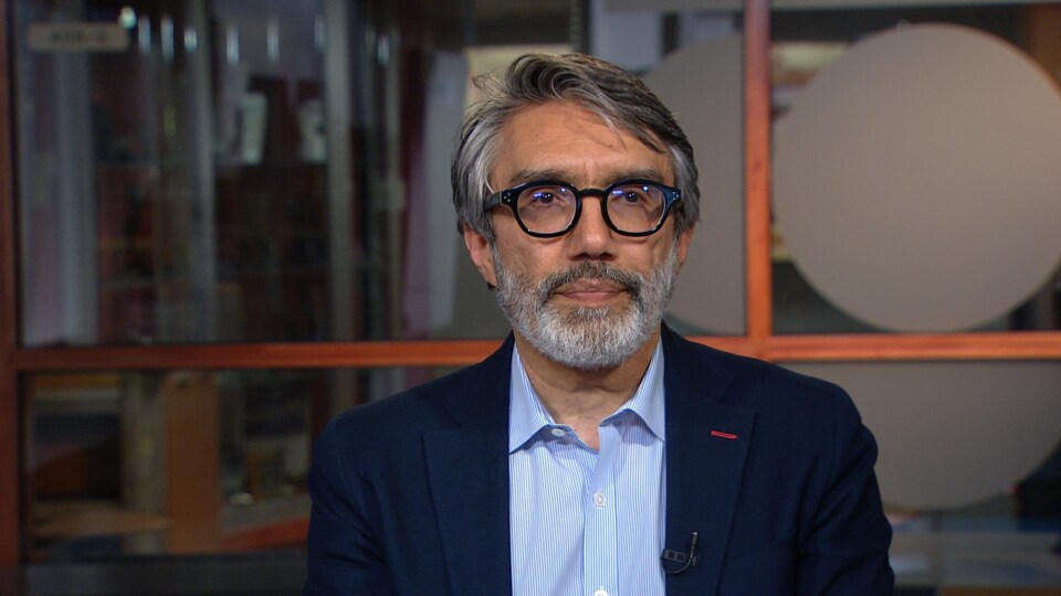 Mehran Ebrahimi, spécialiste de l’aviation, portant des lunettes et une petite barbe. Il regarde la caméra alors qu'il est interviewé dans nos studios de Montréal.