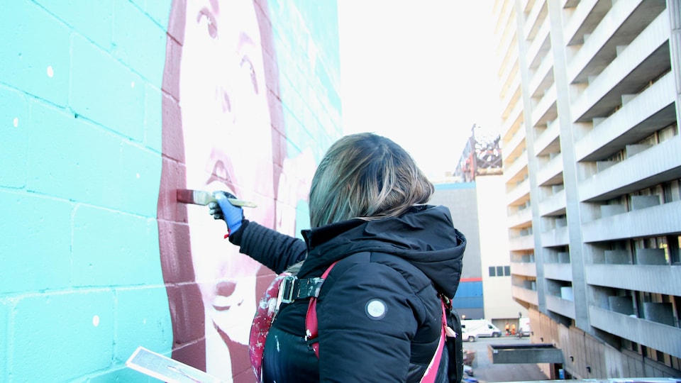 L'artiste Meky Ottawa peint une murale qu'elle a dessinée de la cinéaste abénaquise Alanis Obomsawin, au centre-ville de Montréal.
