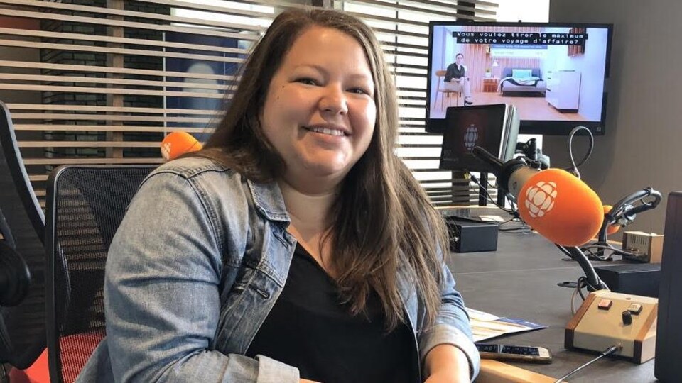 Une jeune femme souriante pose dans un studio de radio