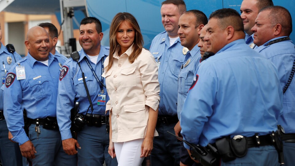 Melanie Trump est souriante et entourée de de huit policiers.