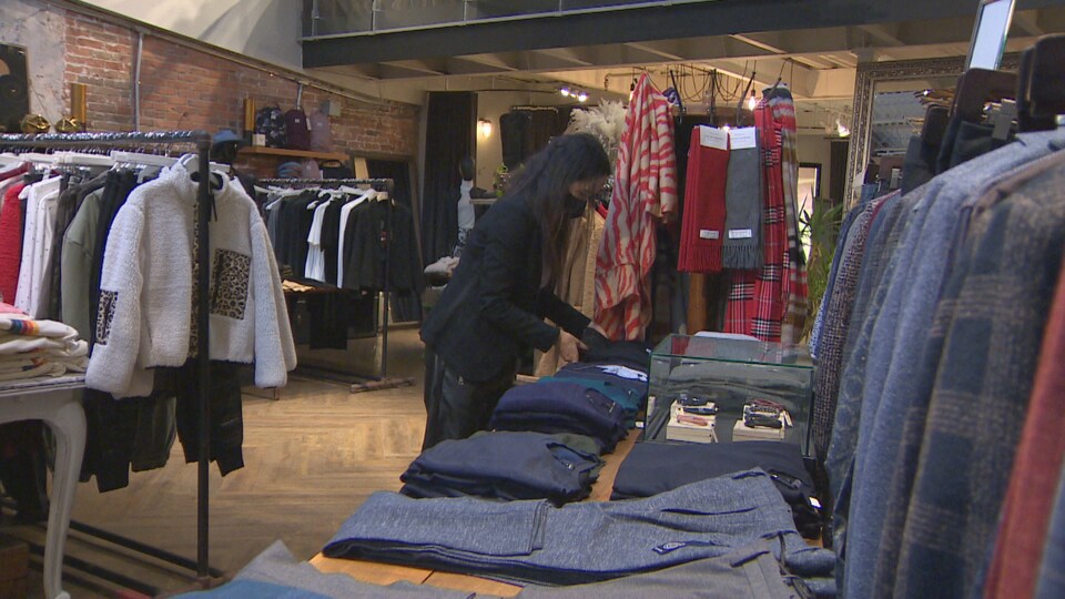 Une femme plie des vêtements dans une boutique.