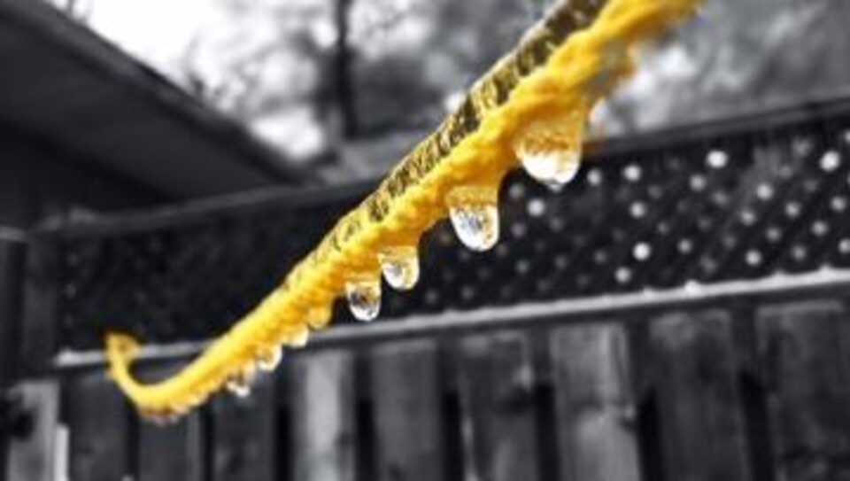 Des gouttes d'eau glacées pendent d'une corde jaune.