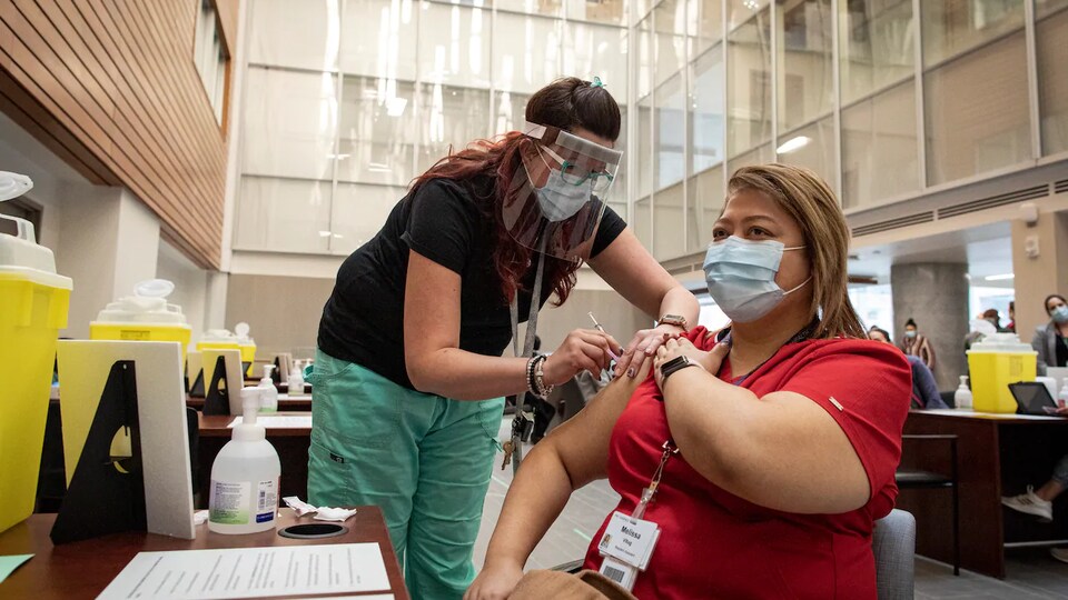 L'infirmière Megan Buehholz administre une dose du vaccin Pfizer-BioNTech contre la COVID-19 à Melissa Vitug.