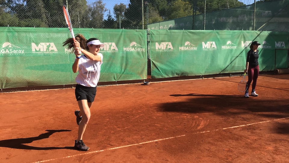 Une joueuse de tennis frappe une balle sur un terrain de terre battue.