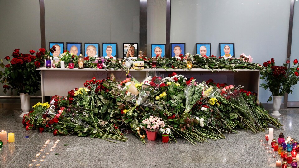 Des fleurs et des chandelles sont placées près de photos de gens tués lors de l'écrasement d'un avion.