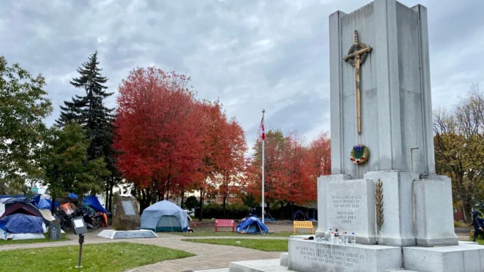 Plusieurs tentes en bordure d'un monument d'un parc vers la fin de l'automne.