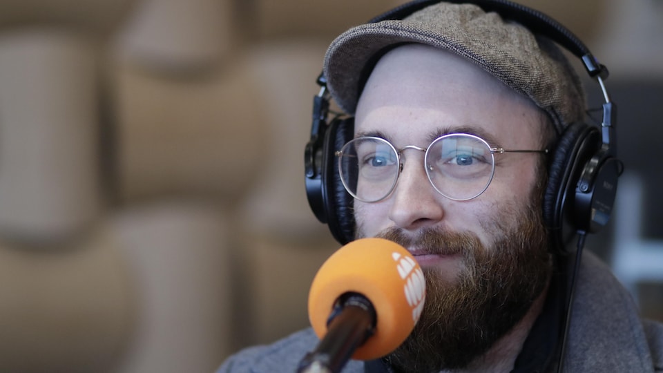 Un homme barbu portant des lunettes qui parle à un micro
