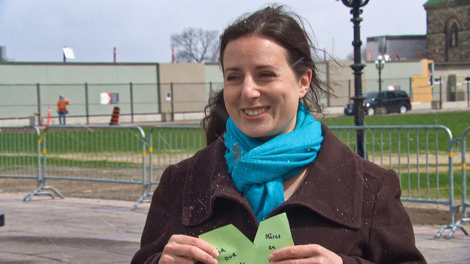 La jeune mère, devant le parlement à Ottawa, tient un coeur vert dans les mains.