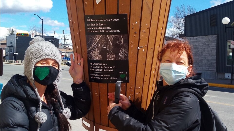 Deux femmes collant une affiche pour sensibiliser à l'environnement