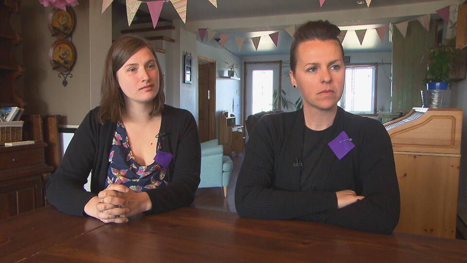 Les deux mamans assises à une table en entrevue avec un carré mauve sur leur chandail