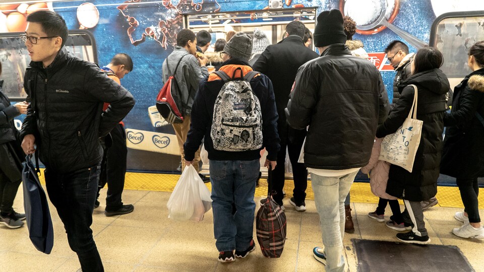 Des gens chargÃ©s de sacs d'achats entrent dans le mÃ©tro Ã  la station Dundas qui dessert le centre Eaton.