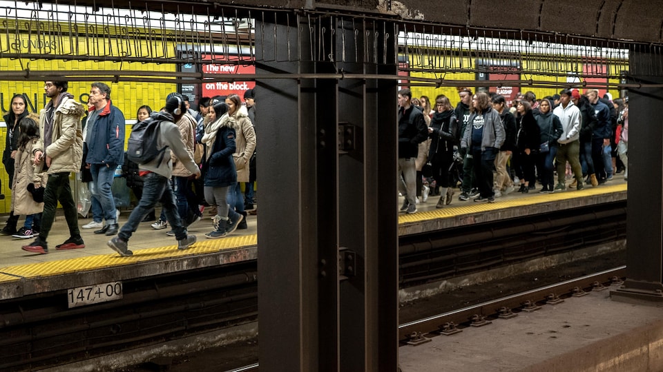 Une foule de gens situÃ©e de l'autre cÃ´tÃ© du quai du mÃ©tro de Toronto se dirige vers la sortie qui mÃ¨ne au centre Eaton.