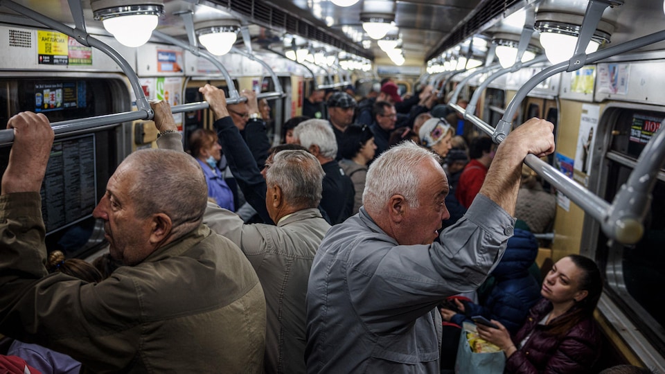 People standing or sitting in a subway car. 